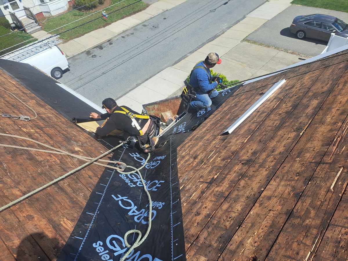 Roofers stripping a roof down to the board sheathing, street and houses seen from above