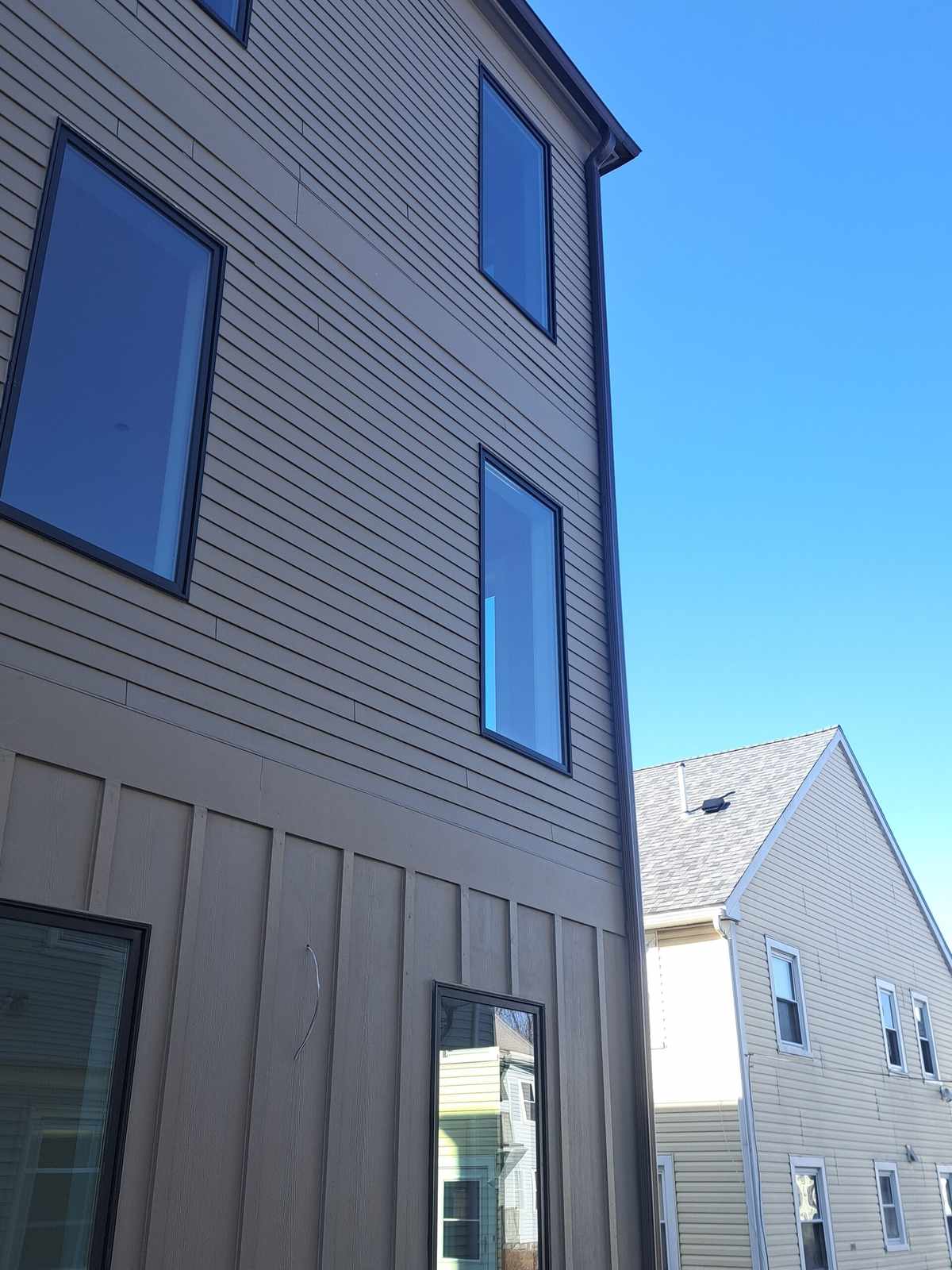 Downspout running down beige board-and-batten siding