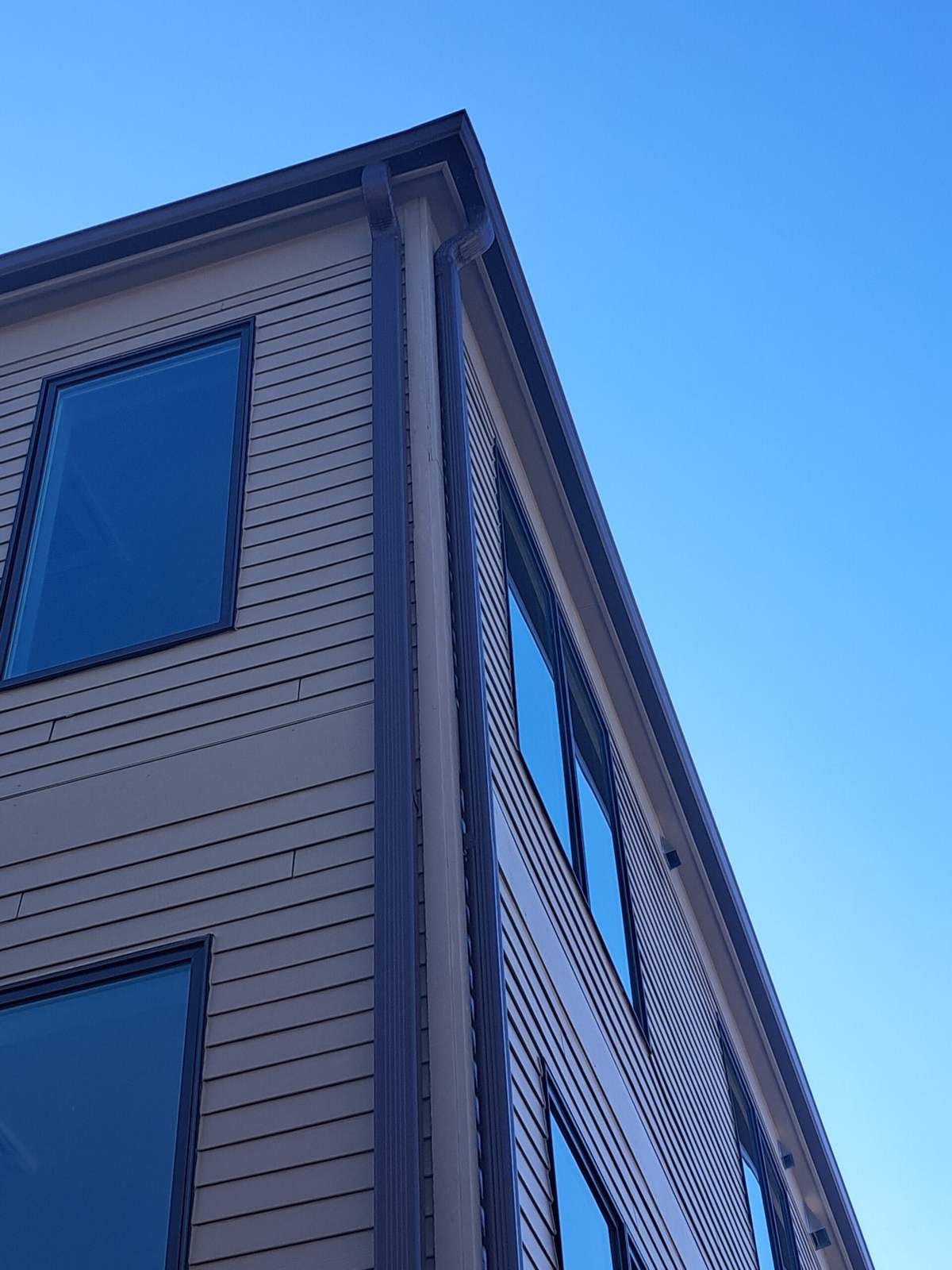 Corner downspout on a new building against a blue sky
