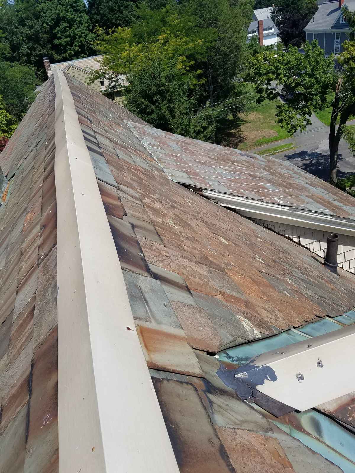 Old slate roof with a new metal ridge cap seen along the ridge