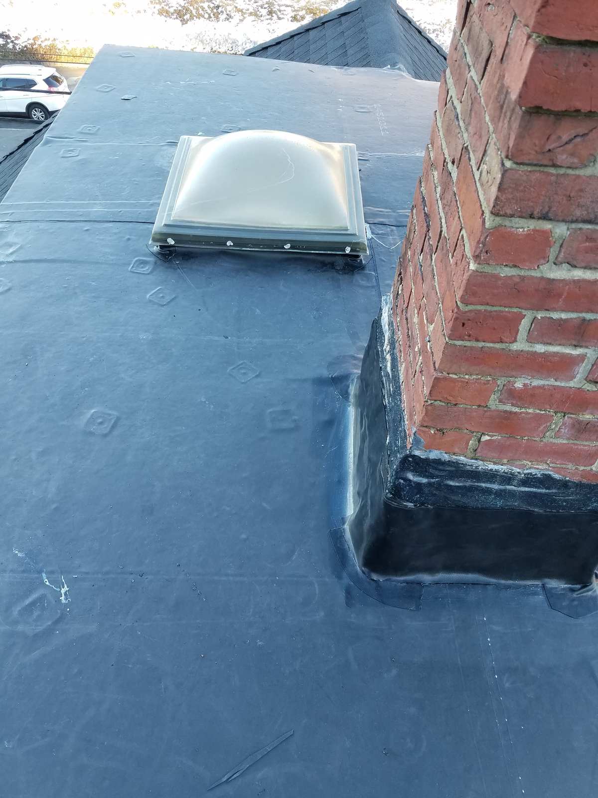 Rubber roof repaired around a skylight and brick chimney with new flashing