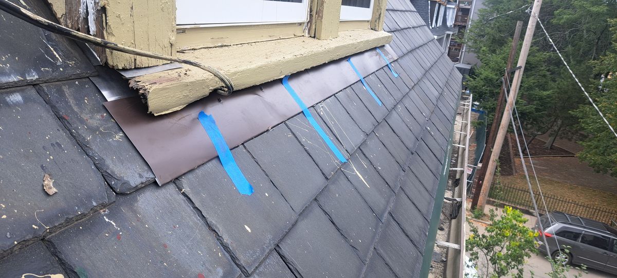 Slate roof with new metal flashing installed where it meets a wall