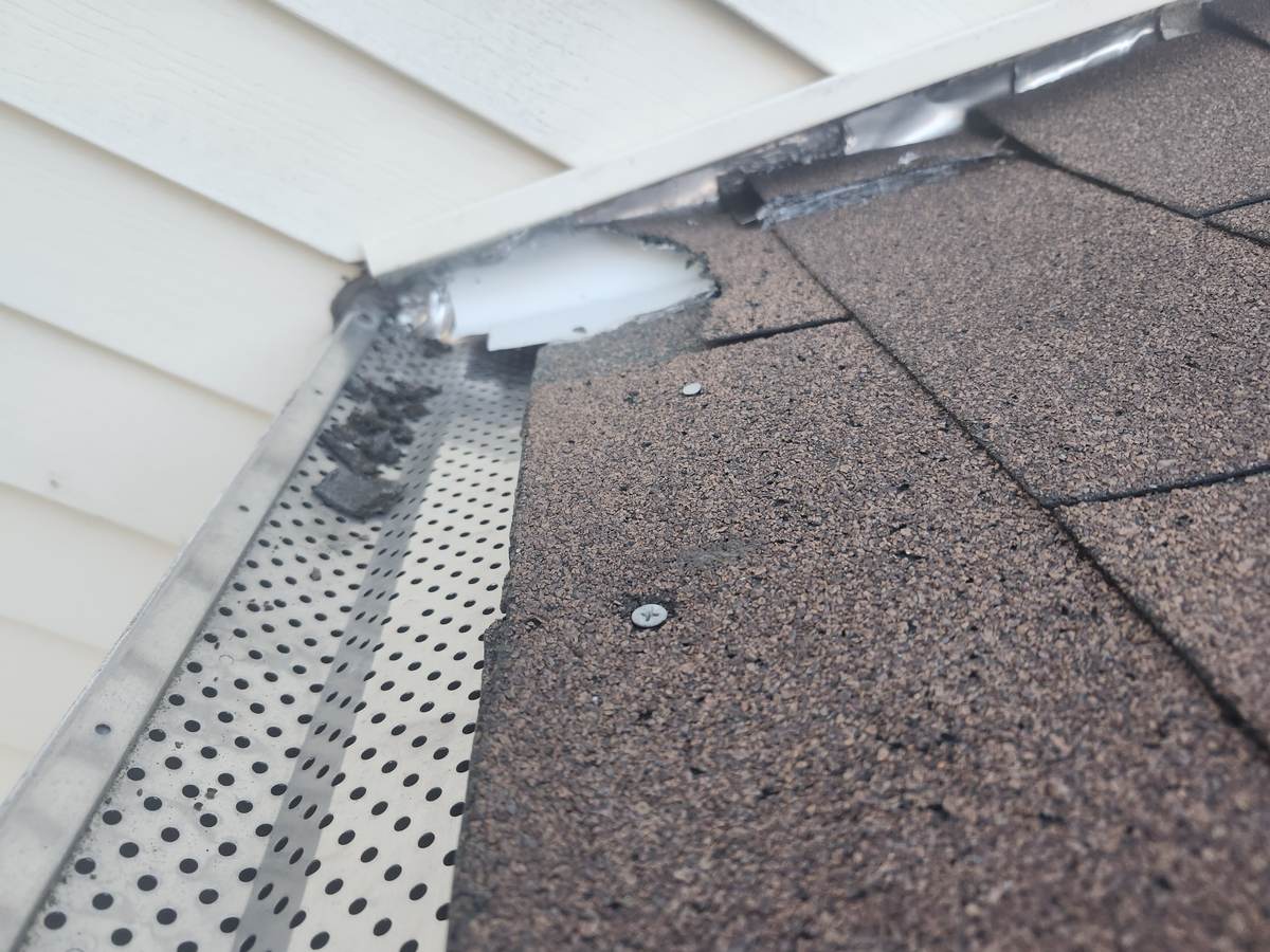 New drip edge and gutter guard at the edge of a brown shingle roof