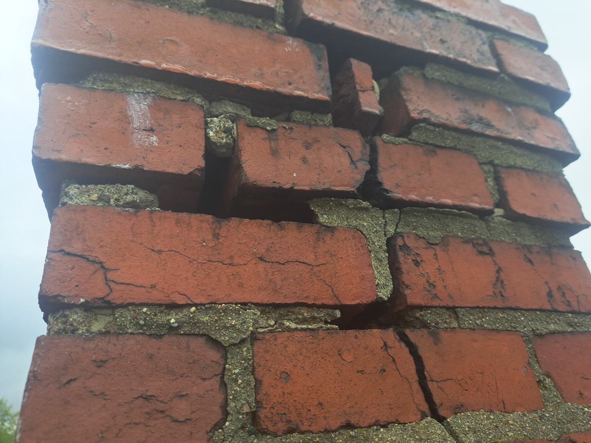 Brick chimney with cracked, deteriorated mortar joints before repointing