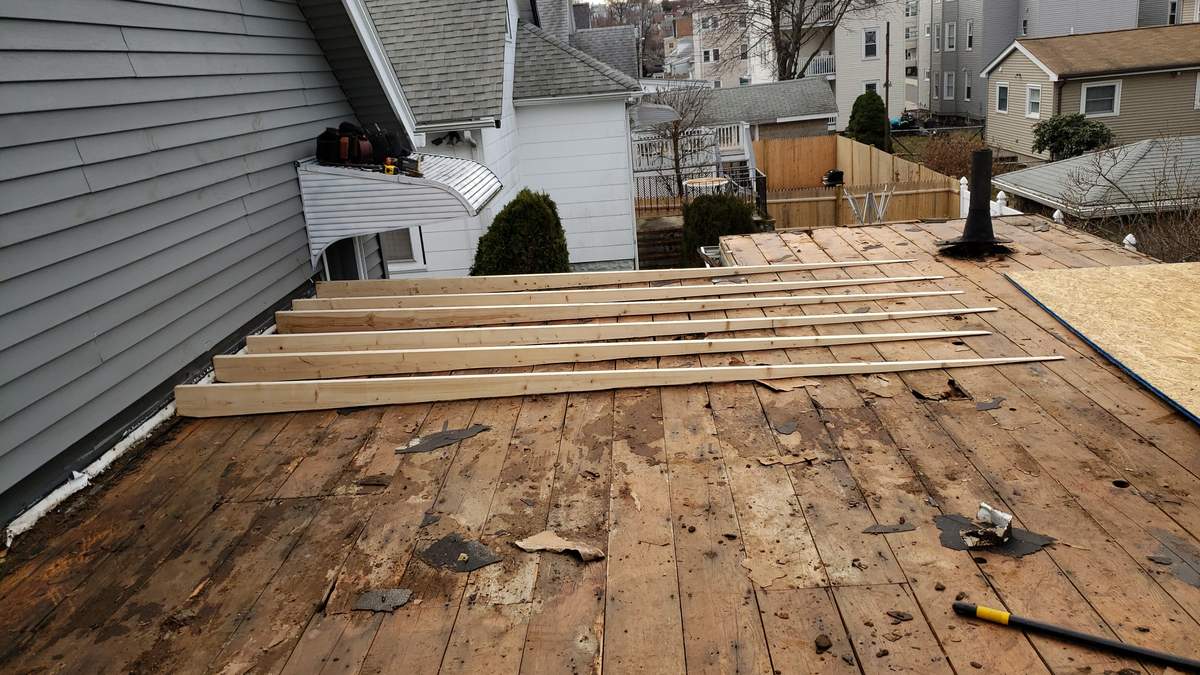 New lumber joists laid over an old flat roof deck before the rubber membrane