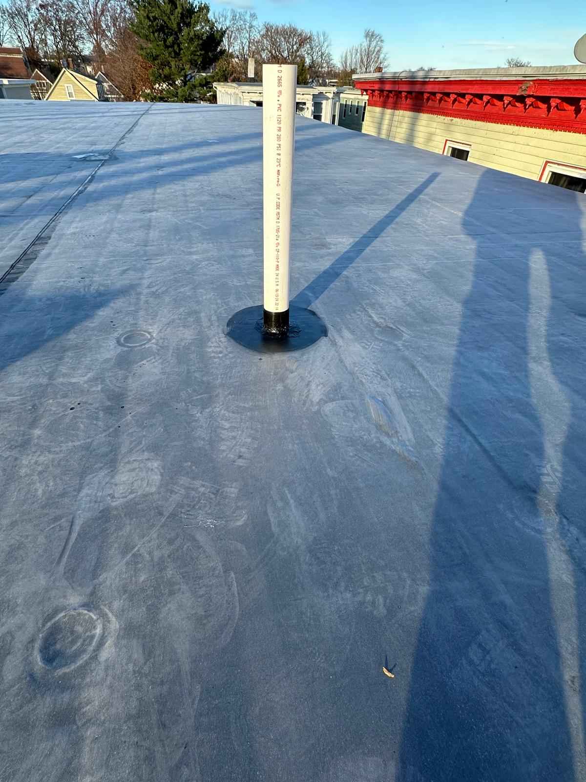 Flat rubber roof with a pipe boot, city buildings behind