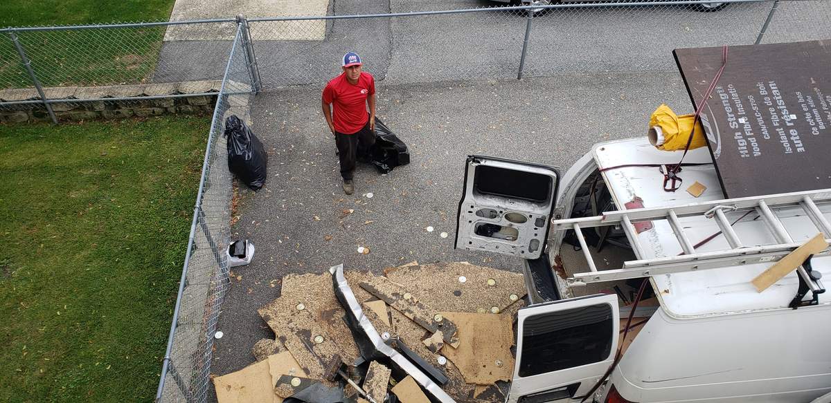 View from a flat roof down to a work van and tear-off debris in a driveway