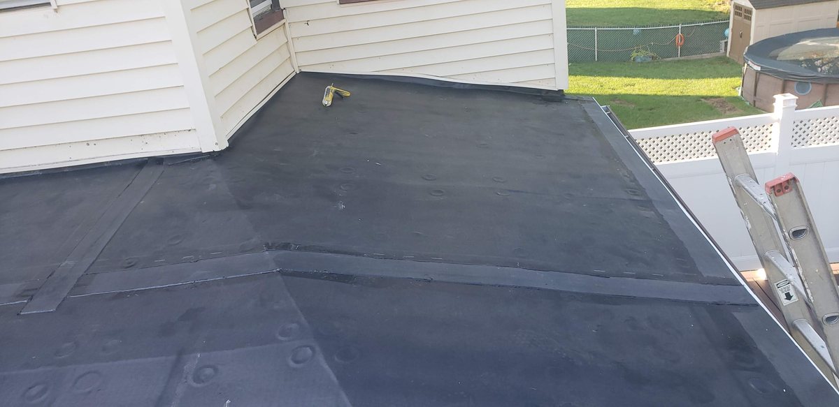 Finished black rubber roof on a flat section between two white-sided walls