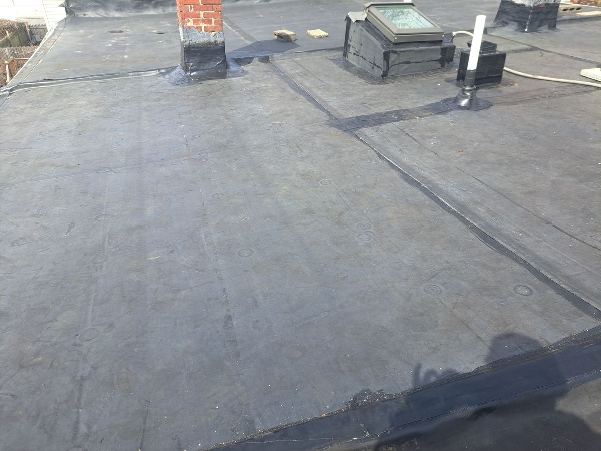 Finished gray rubber roof with chimney, skylight and pipe boots