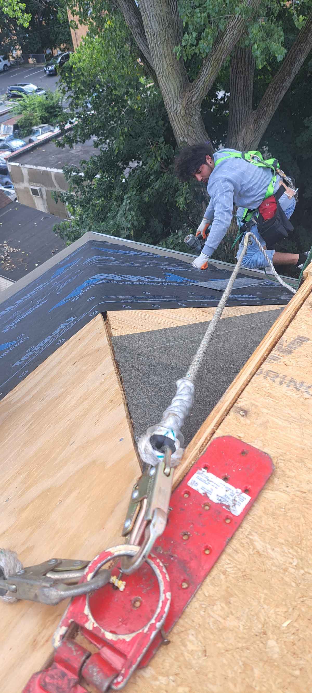 Roofer applying adhesive on a new flat roof deck next to a parapet