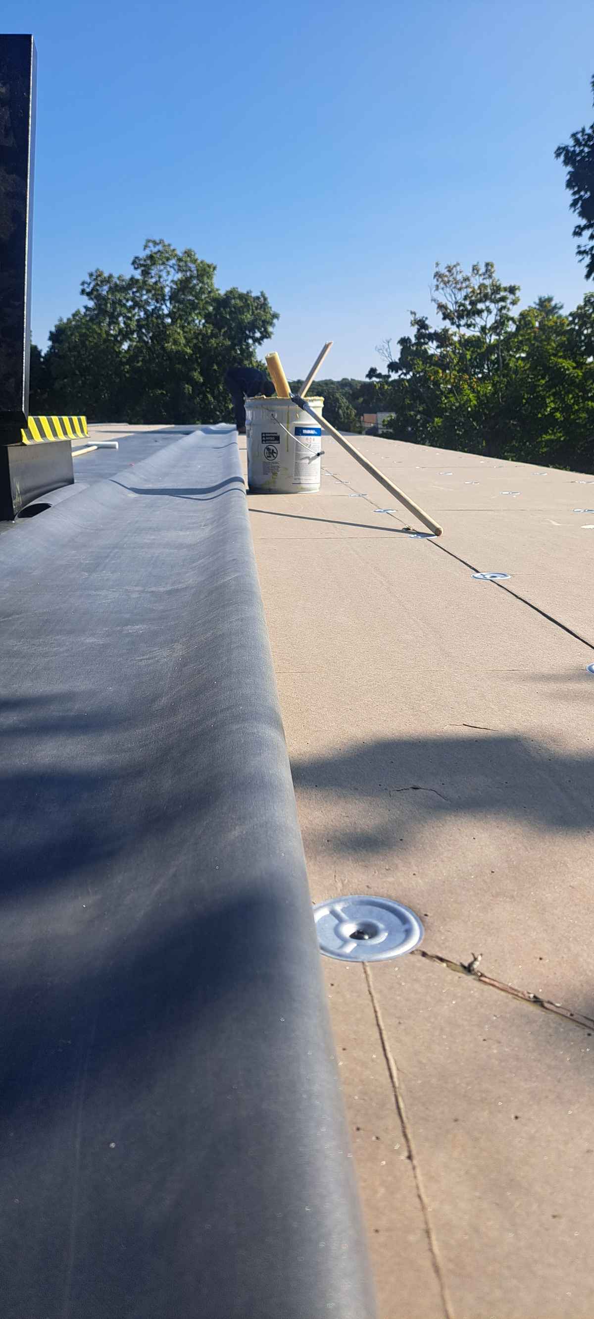 Insulation boards fastened on a flat roof with rubber flashing at the edge