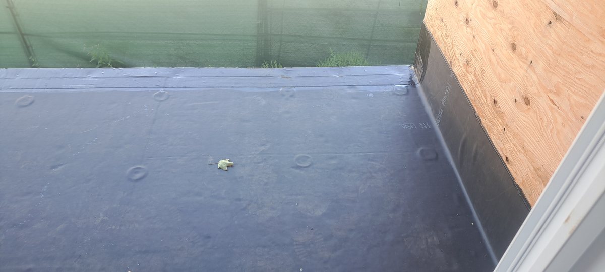 Rubber membrane on a flat roof deck with plywood parapet and white trim