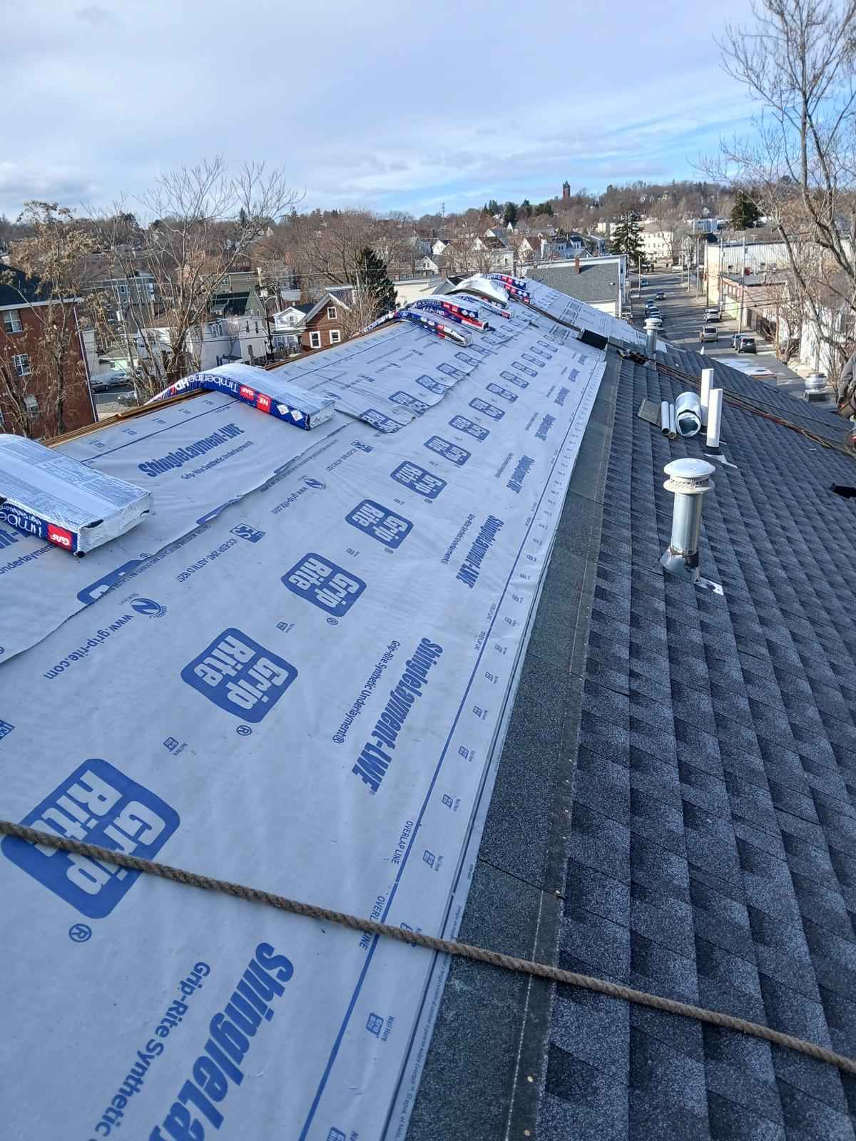 Synthetic underlayment rolled across a roof with new shingles started at the eave