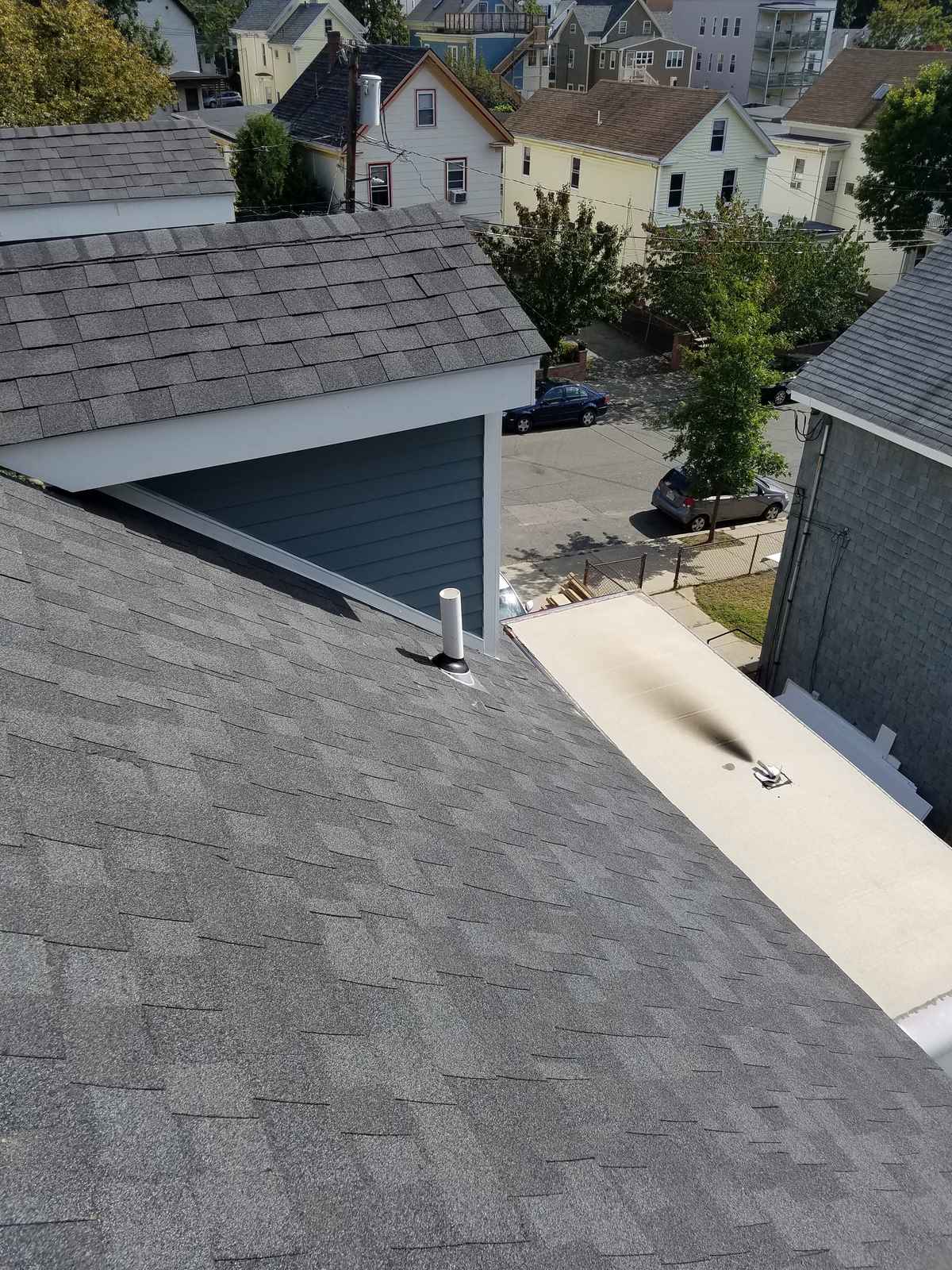 New gray asphalt shingle roof seen from above with neighboring houses