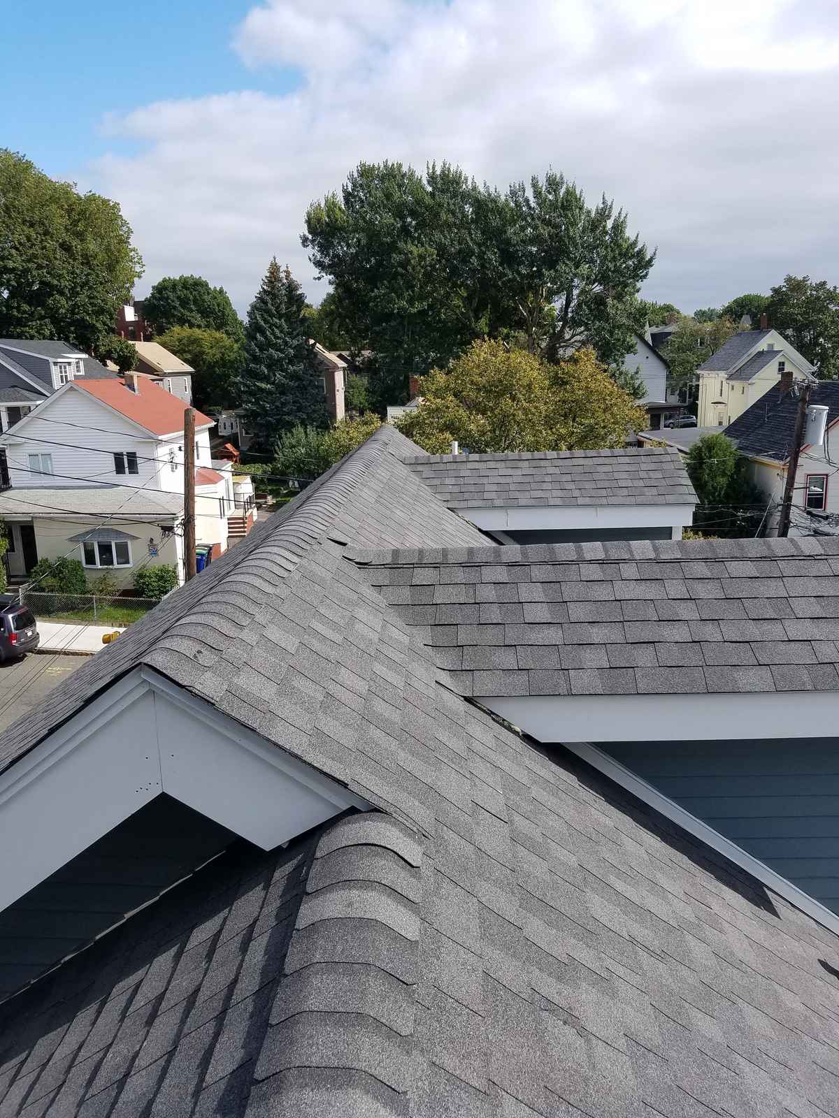 New gray asphalt shingle roof ridge and gables seen from above