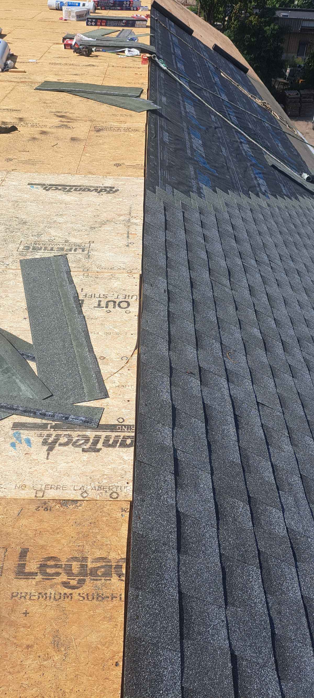 Close-up of new asphalt shingles being laid over underlayment at a roof edge