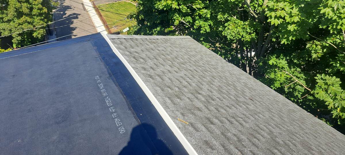 New gray shingle roof meeting a flat rubber roof section