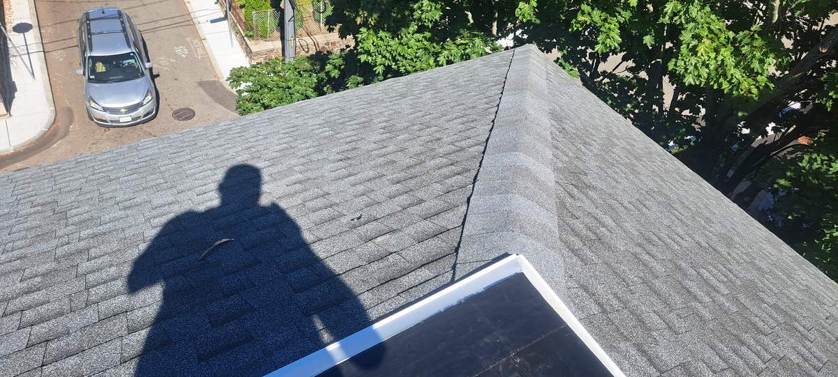 Hip and ridge of a new gray shingle roof seen from above
