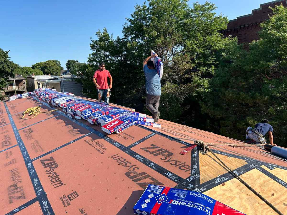 Roof deck with ZIP System sheathing and shingle bundles staged, roofers at work