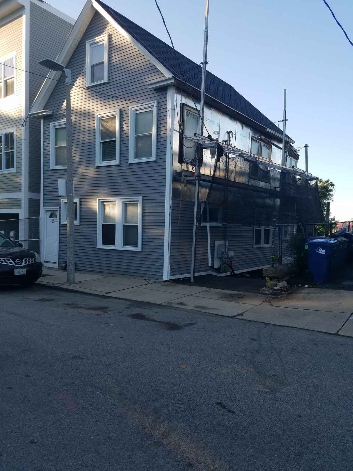 Two-story house with new gray vinyl siding and white trim seen from the street