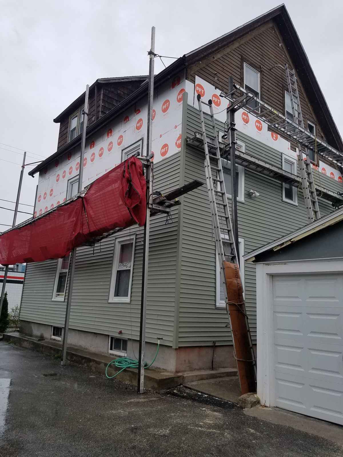 House under siding replacement with scaffolding, green siding and house wrap